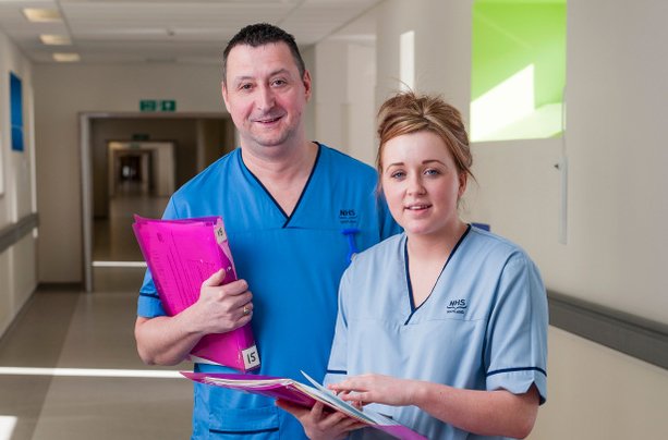 A male Staff Nurse and female Nursing Auxillary looking at the camera