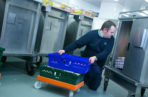 A male staff member loads up a steel trolley with catering supplies